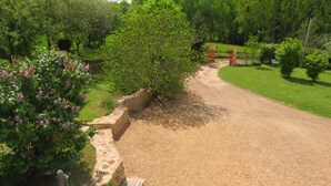 A gravel path leading through a garden with a stone wall and a wooden bench. - Gîte Écoconçu Charmant Proche zoo de la Flèche : Idéal Famille (CLERMONT CREANS)