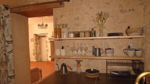 A rustic kitchen with wooden shelves, jars, and vintage kitchenware. - Gîte Écoconçu Charmant Proche zoo de la Flèche : Idéal Famille (CLERMONT CREANS)