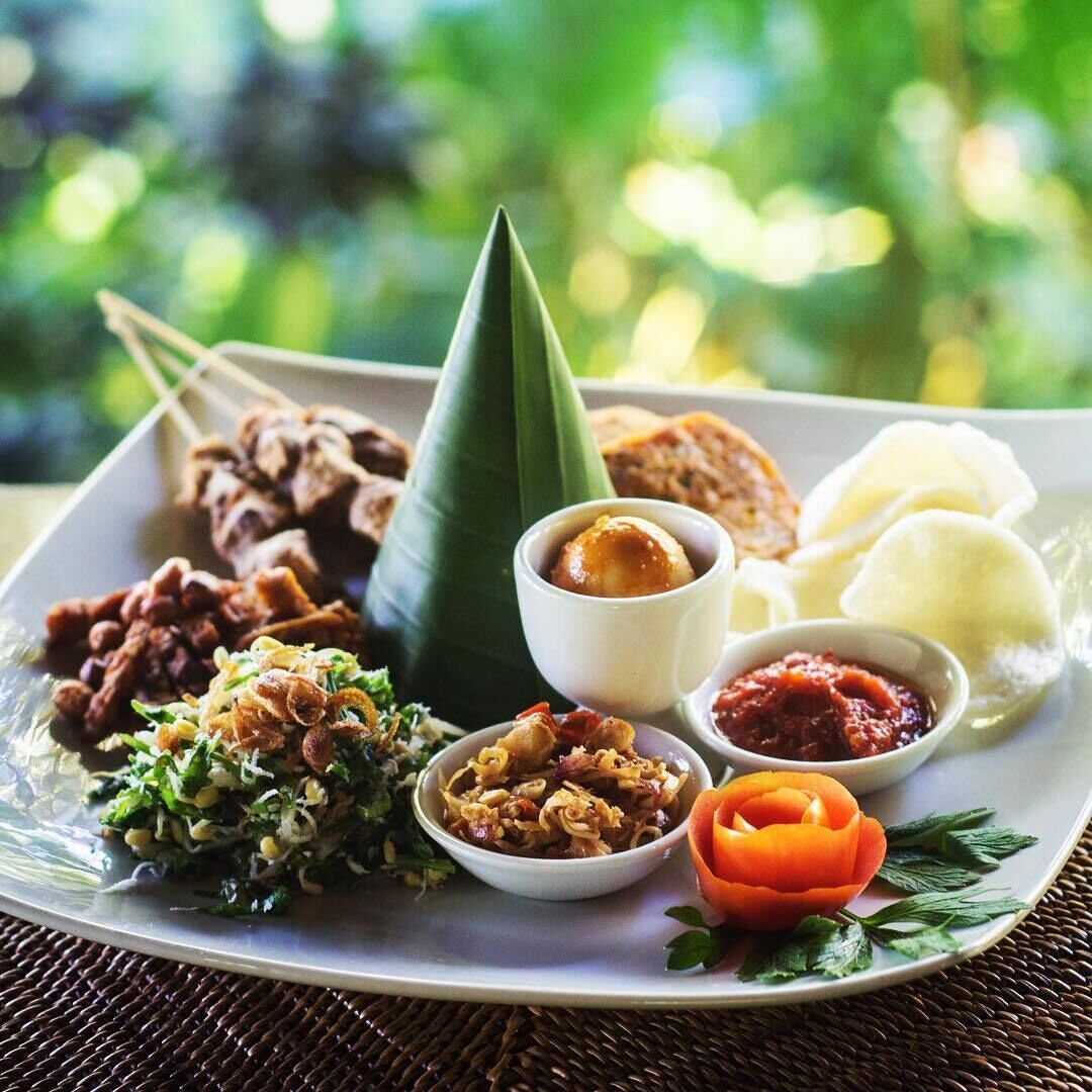 A plate of various Indonesian dishes including satay, rice, and sambal.