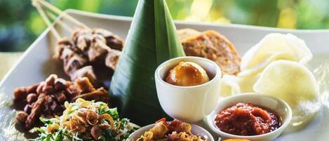 A plate of various Indonesian dishes including satay, rice, and sambal.