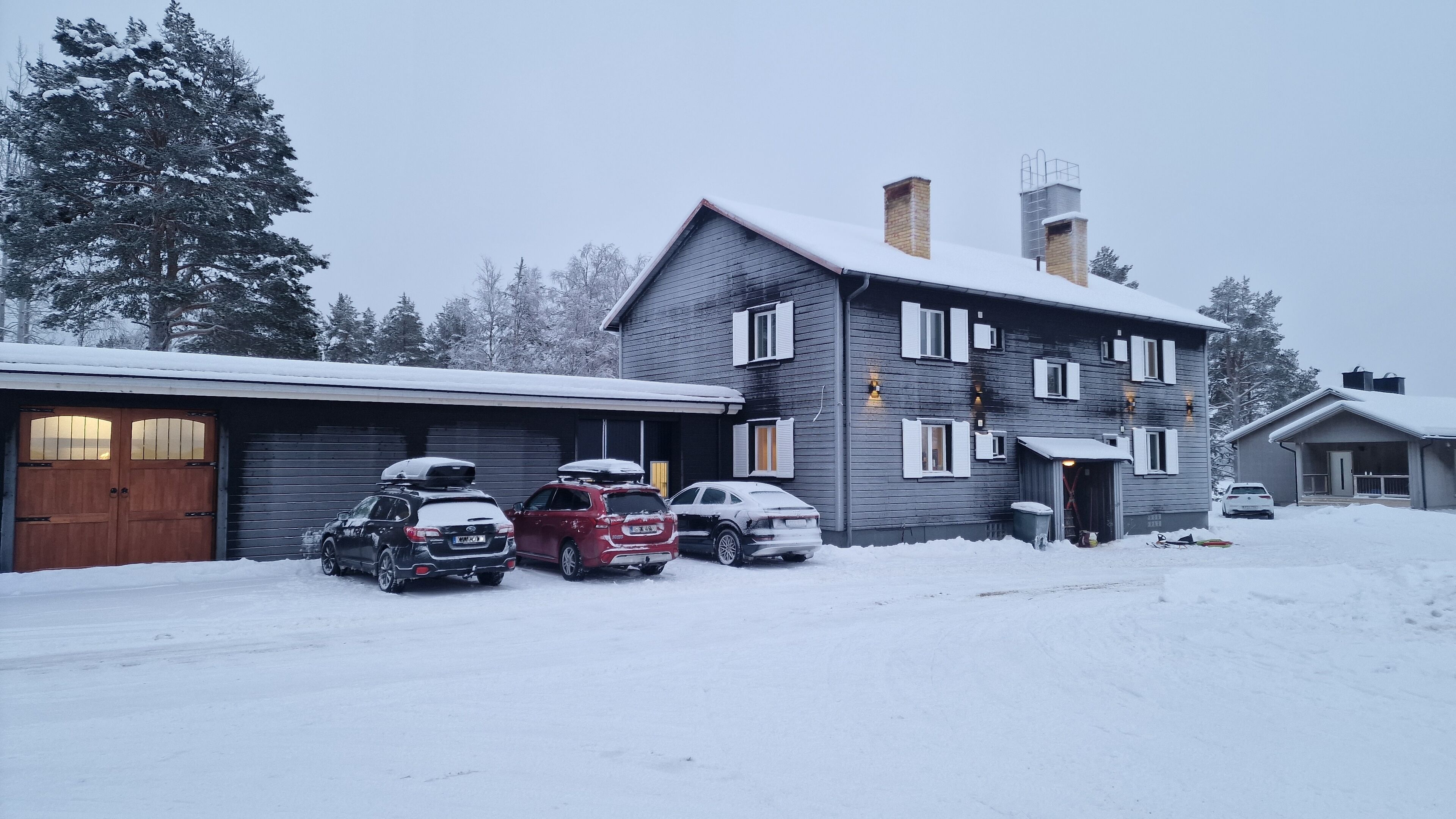 Una casa de dos pisos con garaje y entrada cubierta de nieve.