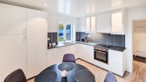 A modern kitchen with white cabinets, a black countertop, and a built-in oven. - Bryggerihusen (Kåbdalis)