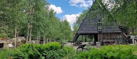 A rustic wooden structure surrounded by lush greenery and trees.