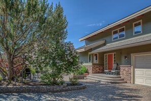 A two-story house with a front porch, a garage, and a well-maintained garden with flowering trees.