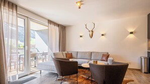 A modern living room with a sectional sofa, two armchairs, a coffee table, and a glass door leading to an outdoor area. - TOP 5 - Luxuriöses Apartment in der Tiroler Zugspitzarena (Berwang)