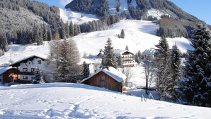 A snow-covered mountain landscape with a chalet-style building and a ski resort in the background. - TOP 5 - Luxuriöses Apartment in der Tiroler Zugspitzarena (Berwang)