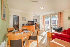 Un espacio habitable bien iluminado con una mesa de comedor, sillas, un sofá rojo y una cocina al fondo.