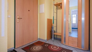 A hallway with a wooden door, a metal ladder, and a small wooden cabinet. - Cozy vacation apartment by the sea with balcony, WiFi & parking space (Koserow)
