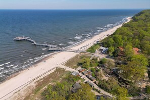 An aerial view of a coastal area with a beach, a pier, and a cluster of buildings. - Cozy vacation apartment by the sea with balcony, WiFi & parking space (Koserow)