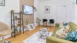 A modern living room with a TV, a sofa, a coffee table, and a bookshelf.
