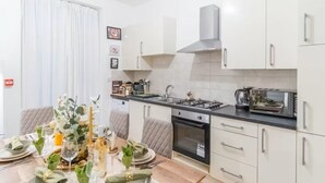 A modern kitchen with white cabinets, a gas stove, a microwave, and a coffee maker.