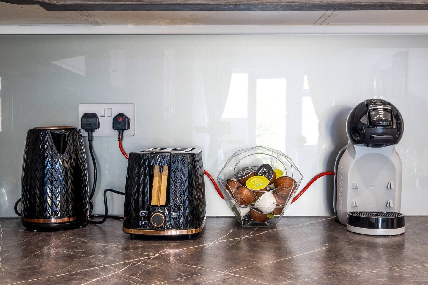 A kitchen with three appliances: a coffee maker, a toaster, and a rice cooker.