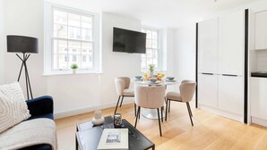 A modern living room with a sofa, coffee table, and a dining area with chairs and a table set for breakfast.