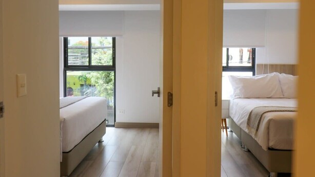 A modern bedroom with a large window, a bed, and a door leading to another room. - w* | Homey 3BR with Balcony in Premium Miraflores (Miraflores)