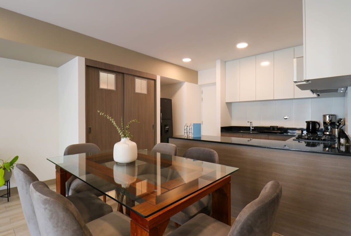 A modern kitchen with white cabinets, a black countertop, and a built-in stove.