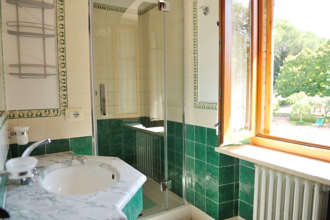 A bathroom with a sink, mirror, and shower.