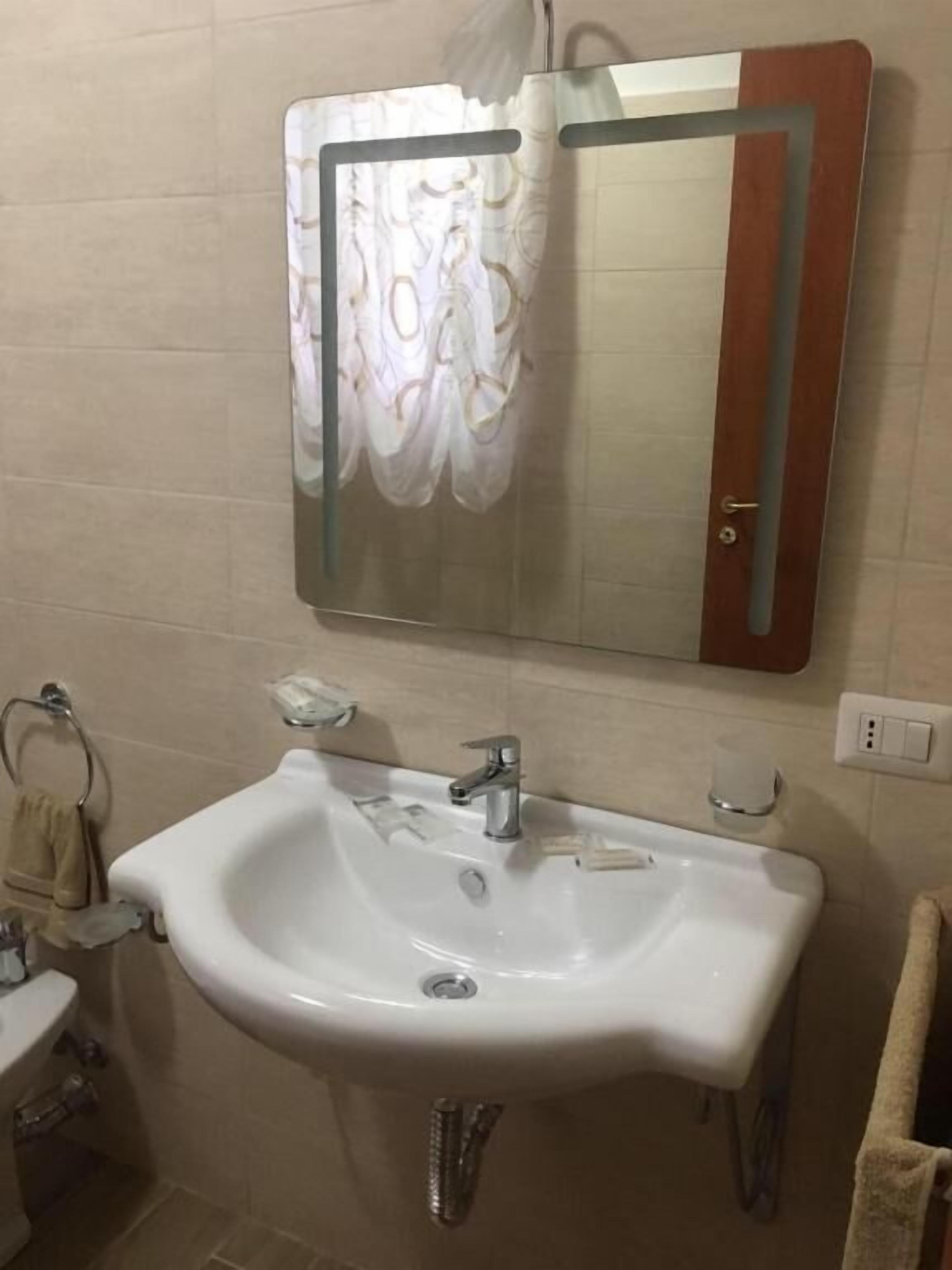 Une salle de bain avec un lavabo blanc, un miroir et un porte-serviettes.