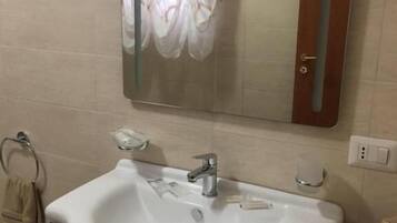 Une salle de bain avec un lavabo blanc, un miroir et un porte-serviettes.