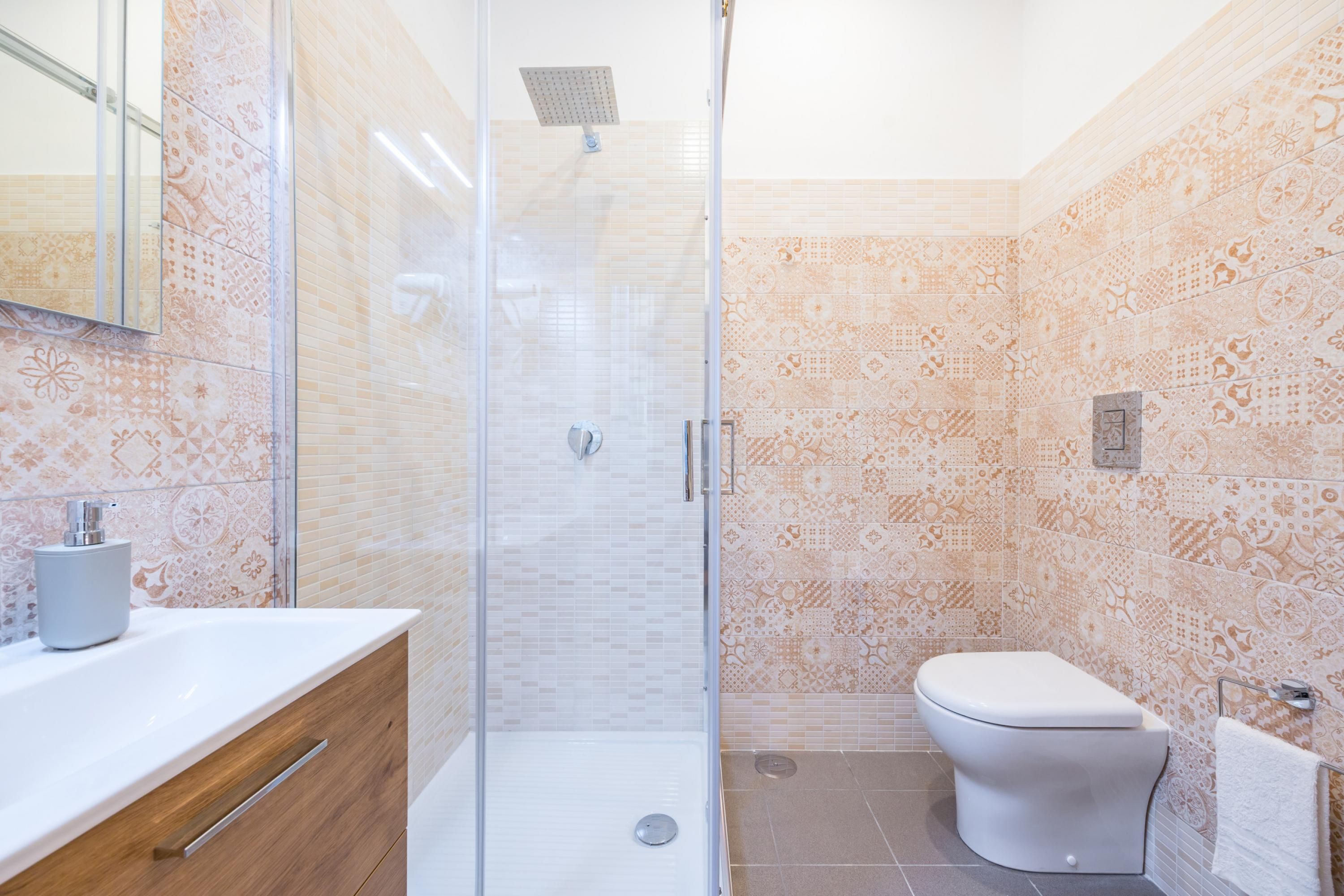 A bathroom with a glass shower enclosure, a white sink, and a toilet.
