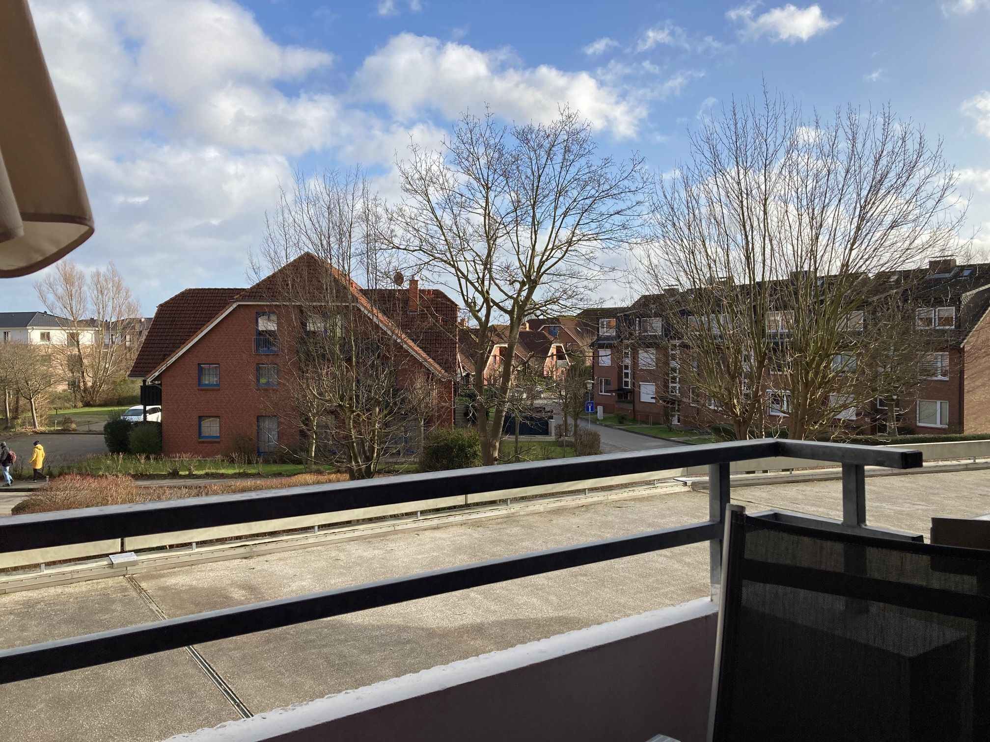 Zona residencial con casas de ladrillo, cielo despejado y una acera.