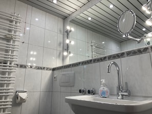 Ein modernes Badezimmer mit einem weißen Waschbecken, einem Spiegel und einem Handtuchhalter.