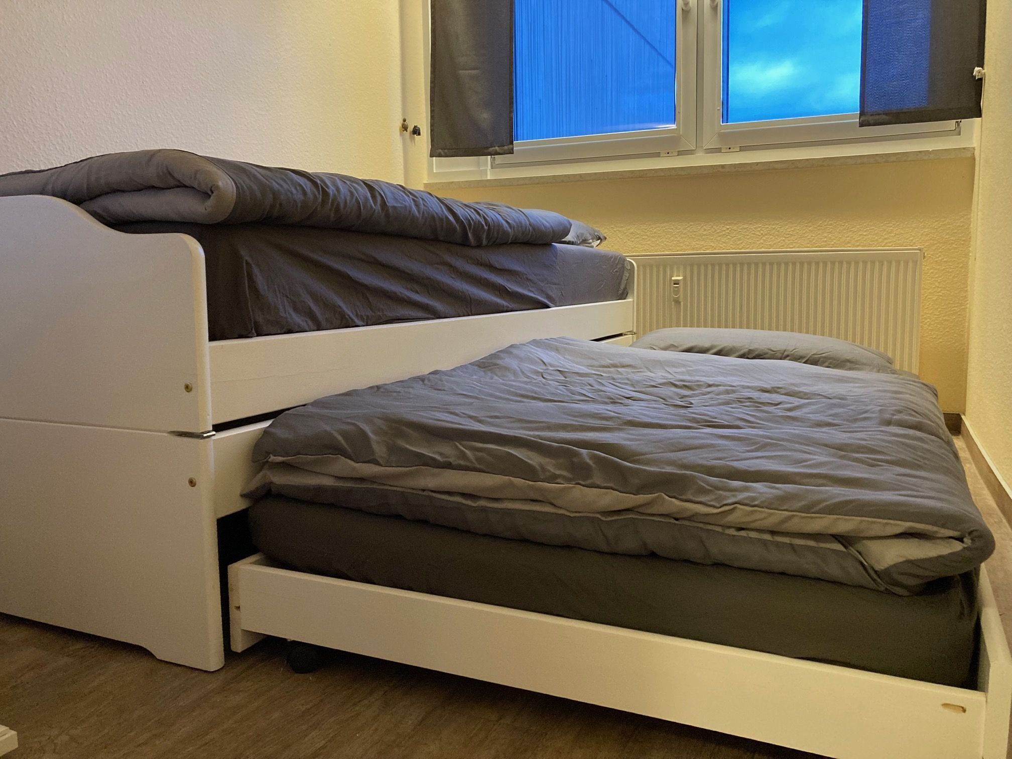 Une petite pièce avec un lit superposé et un lit simple.