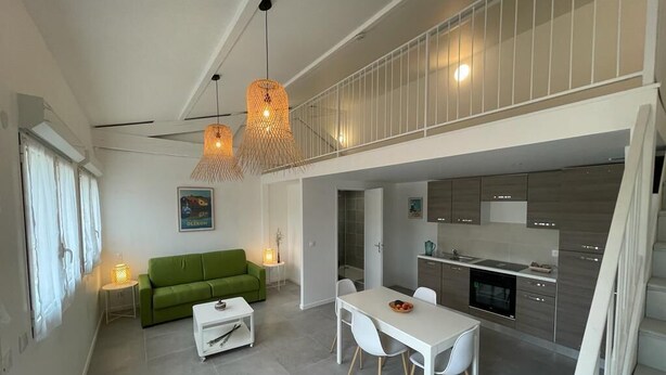 Un espacio moderno para vivir con comedor, sofá verde y cocina.