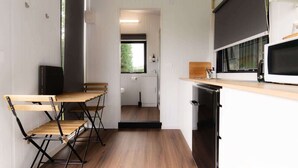 A compact kitchen with a wooden table and chairs, a microwave, and a sink. - Mona Vale Country Estate by Tiny Away (Waikari)