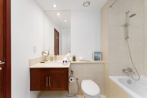 Un baño moderno con un tocador de madera, inodoro, lavamanos y bañera con ducha.