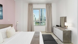 Une chambre d’hôtel avec un lit, une commode, un miroir et une fenêtre avec des rideaux.