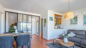 A modern living room with a sofa, a coffee table, and a dining area with chairs and a table. - Dimora Floriana by Sun & Sea (Moraira)