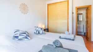 A hotel room with a bed, pillows, a nightstand, a wall decoration, a wooden door, and a bathroom visible through an open door. - Dimora Floriana by Sun & Sea (Moraira)