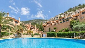 A swimming pool surrounded by buildings with balconies, a clear sky, and greenery. - Dimora Floriana by Sun & Sea (Moraira)