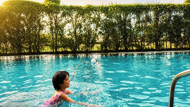 Piscina com água cristalina, cercada por um viveiro.
