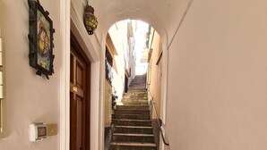 A narrow hallway with a tiled floor leading to a staircase.