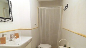 A small bathroom with a white sink, a toilet, and a shower curtain.