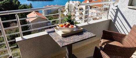 A balcony with wicker furniture, a bowl of fruit, and a potted plant.
