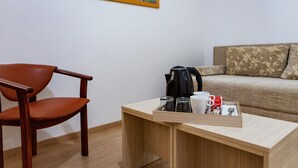 Un escritorio de madera con una bandeja que contiene una cafetera, tazas y una caja de pañuelos. Una silla de cuero marrón está ubicada a la izquierda.