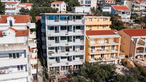 Un edificio residencial de varios pisos con balcones, una antena parabólica y una escalera visible.