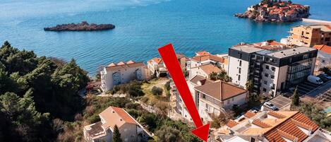 A coastal town with terracotta-roofed buildings, a rocky outcrop, and a clear view of the sea.