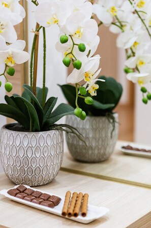 Taula amb una orquídia en test, un plat de xocolata i bastons de canela.