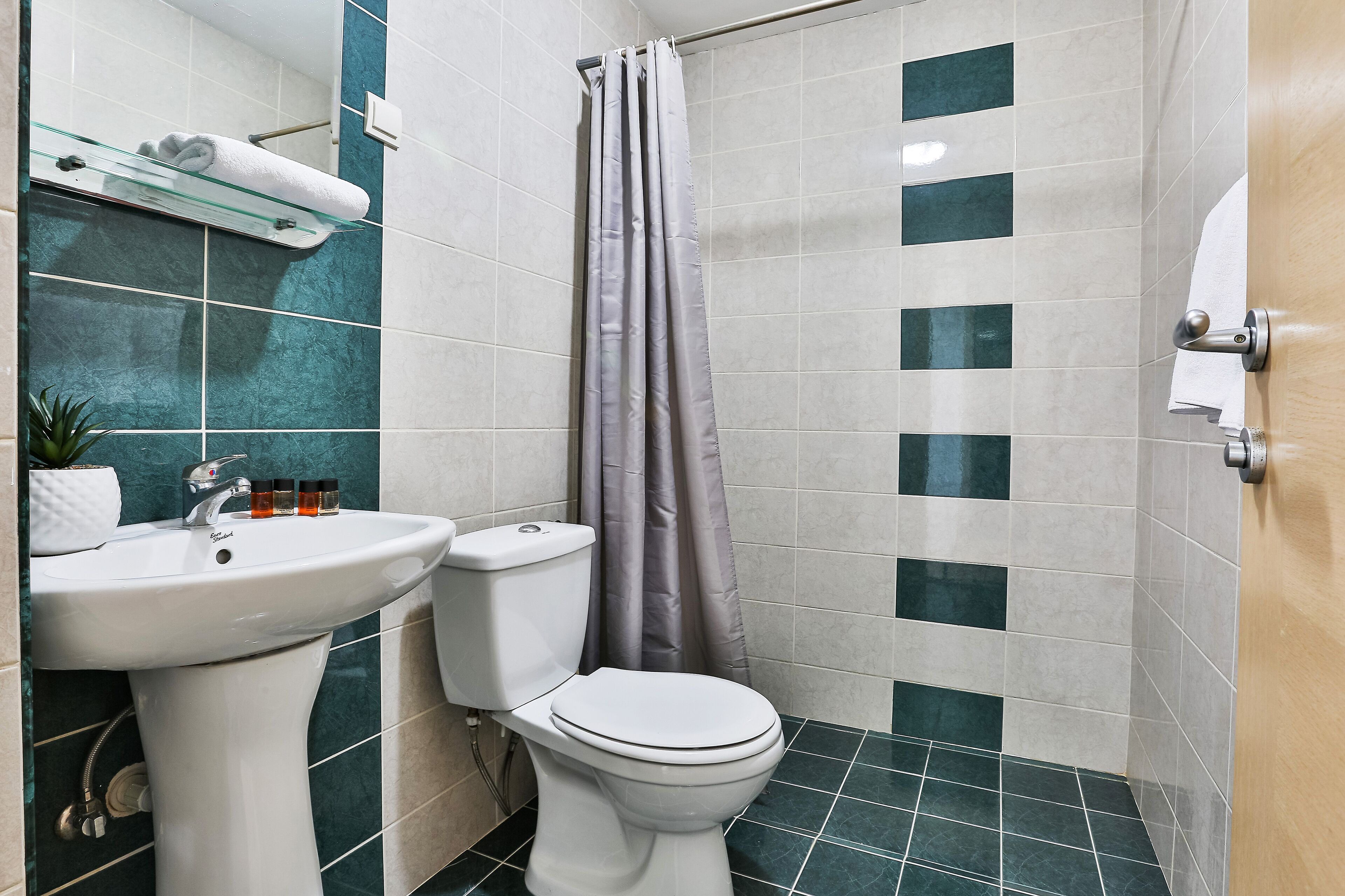 A bathroom with a white sink, toilet, and shower curtain.