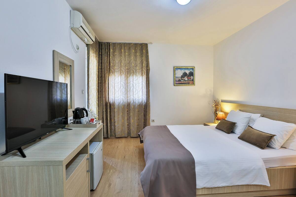 Habitación de hotel con cama, televisión, escritorio y un cuadro en la pared.