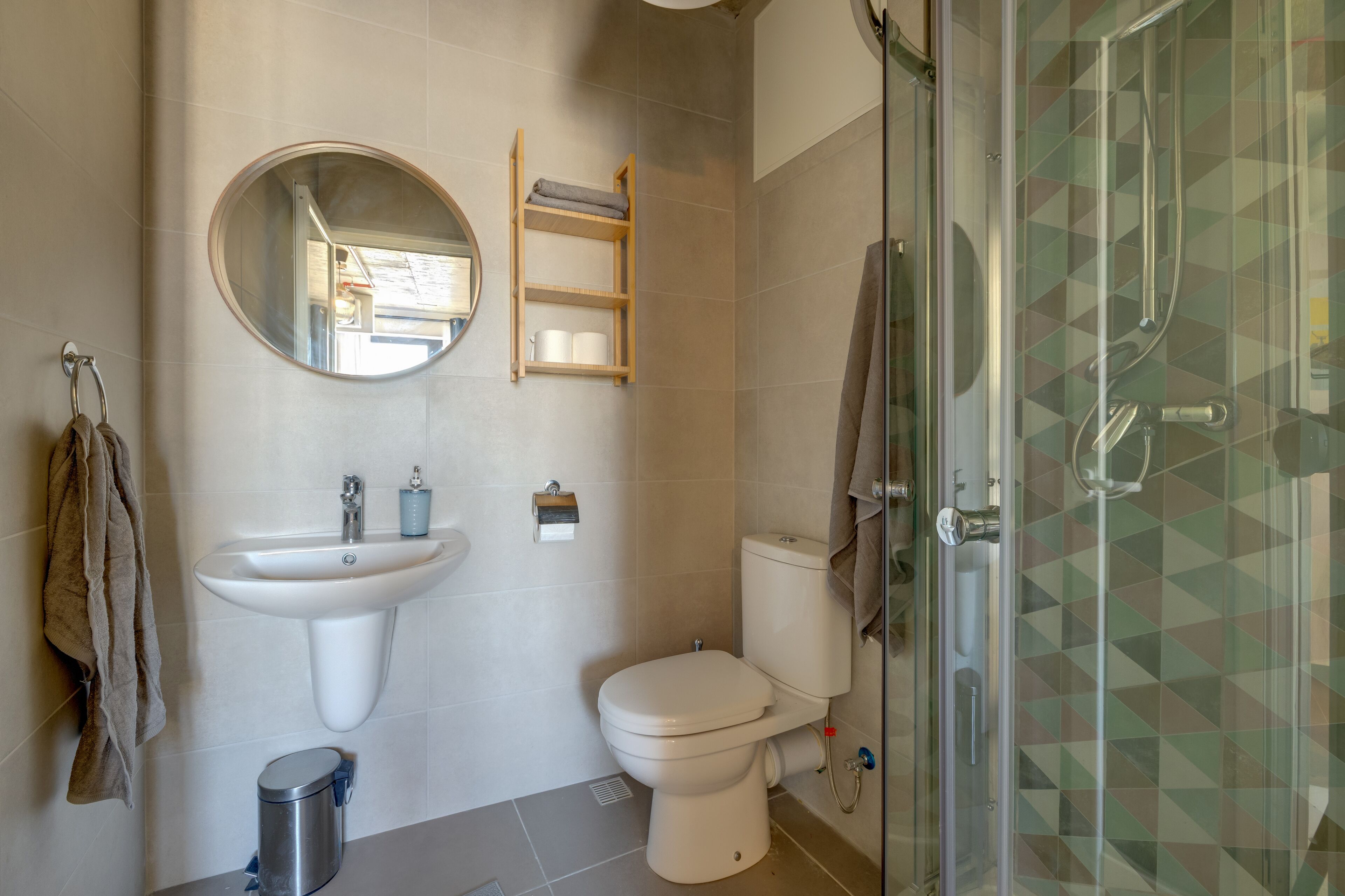 Een moderne badkamer met een wastafel, toilet en douchecabine met glazen wanden.