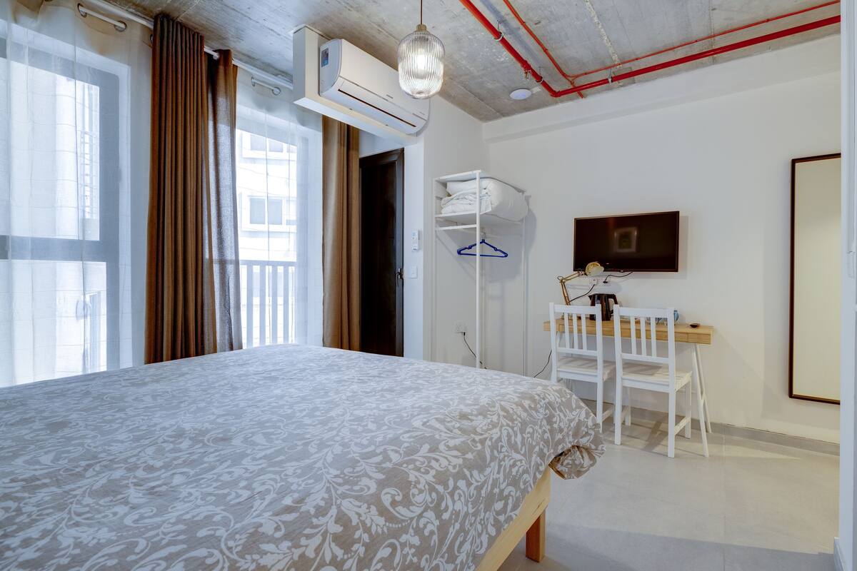 Een slaapkamer met een bed, bureau, stoel en televisie.