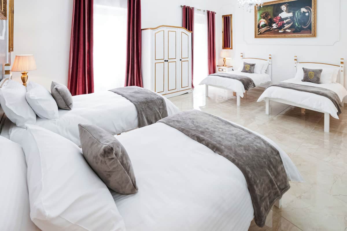 Une chambre d’hôtel avec deux lits, une armoire, un lustre et un tableau au mur.