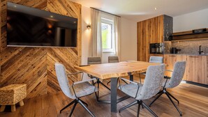 A modern kitchen with wooden cabinetry, a built-in oven, and a flat-screen TV mounted on the wall. - TOP 6 - Großzügiges Apartment mit Bergblick (Berwang)