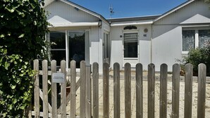 A two-story building with a white exterior, a wooden fence in front, and a sign indicating the location of AirbnB number 29. - Captain's Quarters - Maison en Bord de Plage (Saint-Côme-de-Fresné)