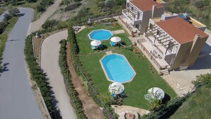 Una extensa propiedad con dos piscinas, un patio y un edificio grande con tejado rojo.