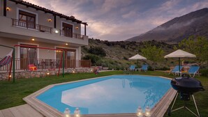 Una piscina con muelle de madera, sillas de descanso y una parrilla.